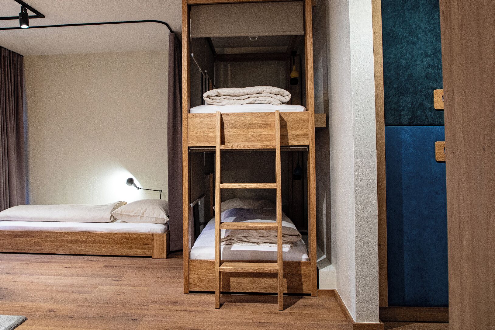 A bunk bed with a ladder, a bedside table with a lamp, and a blue accent wall.