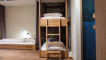 A bunk bed with a ladder, a bedside table with a lamp, and a blue accent wall.