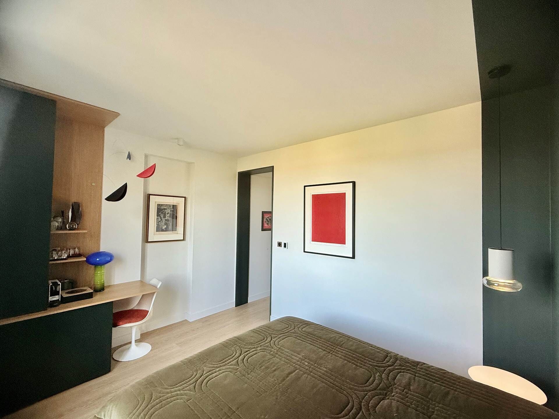 A modern interior with a wooden cabinet, a red framed artwork, and a patterned rug.