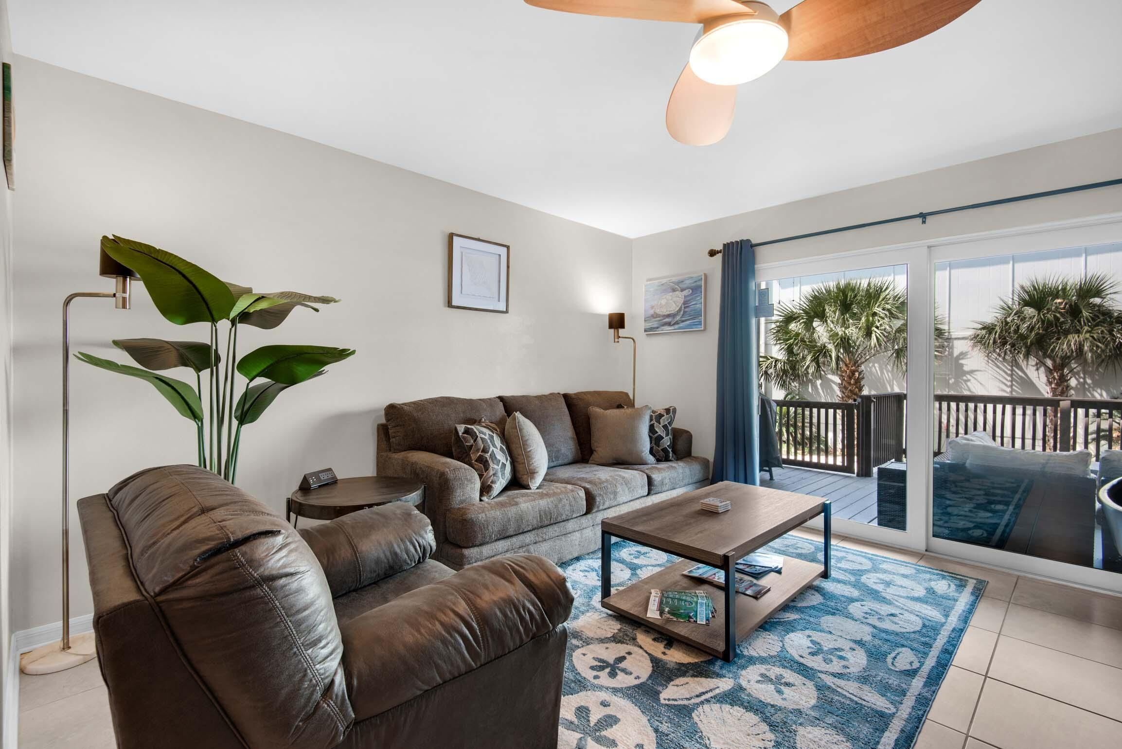 A modern living room with a brown leather sofa, a coffee table, and a large plant.