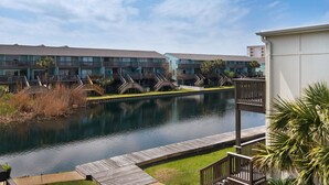 A hotel with a pool, wooden deck, and a view of the water. - Seahorse Siesta (Pensacola Beach)