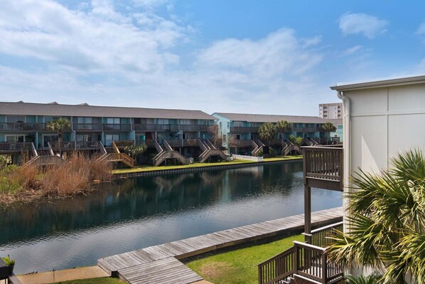 A hotel with a pool, wooden deck, and a view of the water.