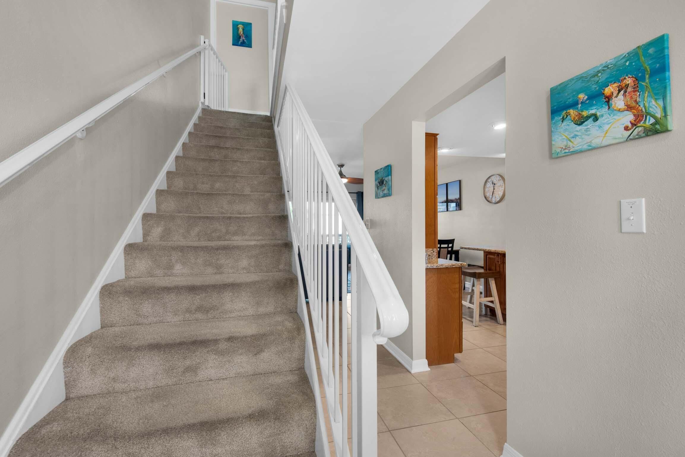A carpeted staircase with white railings leading to a room with a desk and chair.