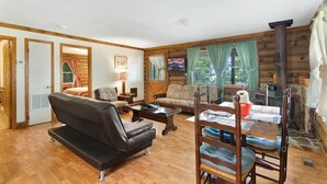 A cozy log cabin interior with a sofa, chairs, a dining table, and a fireplace. -  Carters Lakeside Log Cabin #1. Located in Carters Lake Marina, with boat slip ! (Chatsworth)