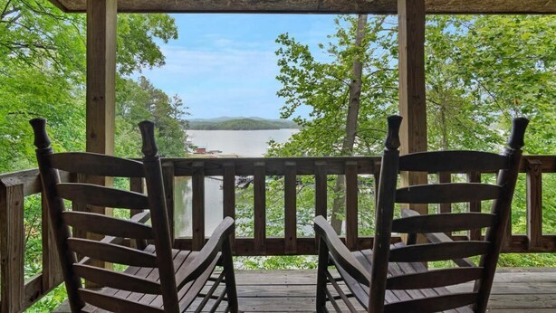 A wooden deck with two chairs facing a scenic view of a lake and mountains. -  Carters Lakeside Log Cabin #1. Located in Carters Lake Marina, with boat slip ! (Chatsworth)
