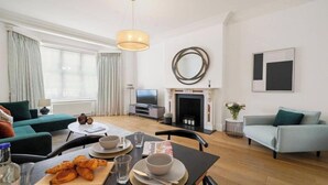 A modern living room with a fireplace, a television, and a dining area with croissants.