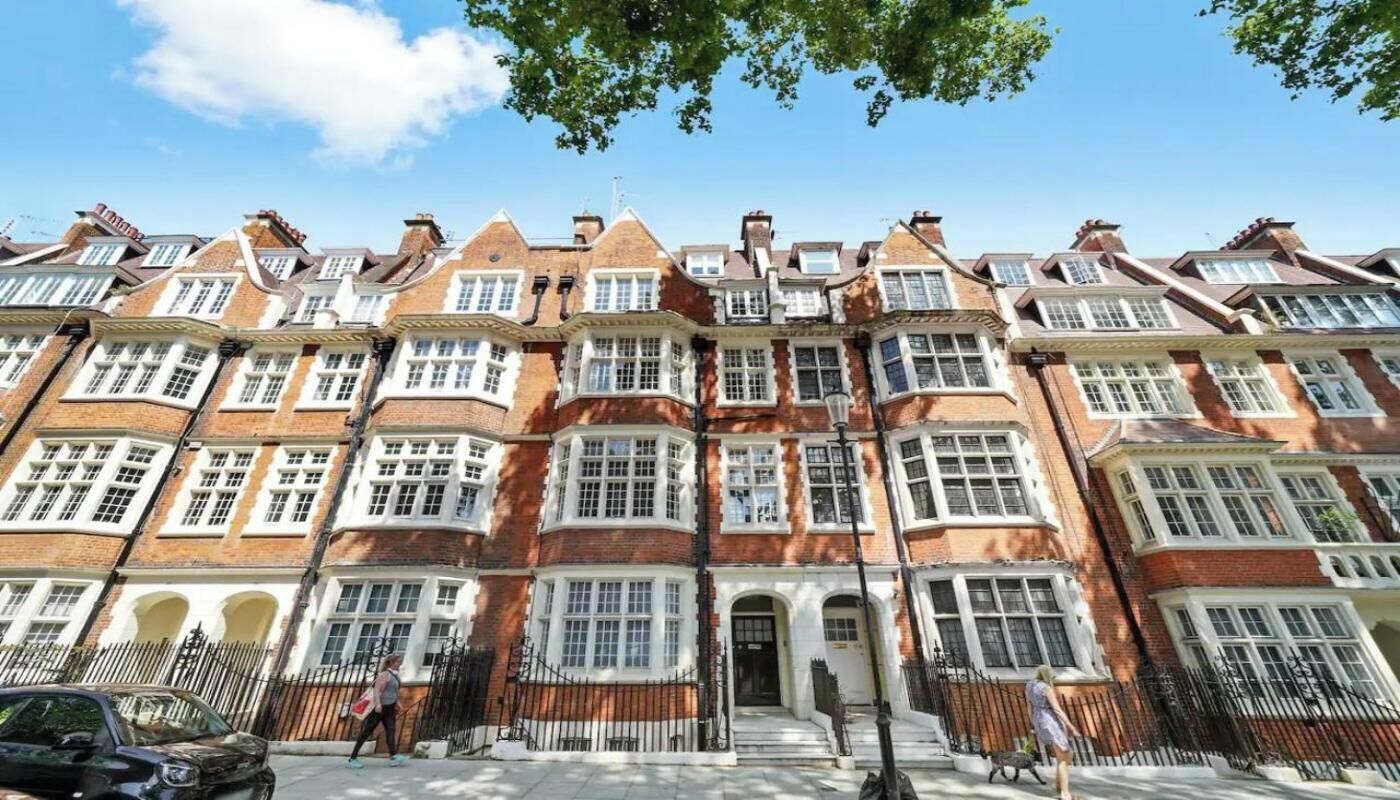 A row of red brick townhouses with white window frames and multiple chimneys.