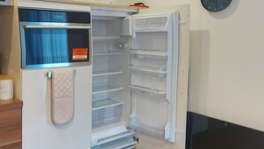 An open refrigerator with multiple shelves and a built-in ice maker. - Modern 2-bed Apartment -12 Min Walk to Centre (Sheffield)