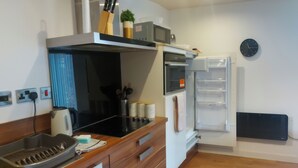 A compact kitchen with a microwave, oven, and refrigerator. There are wooden cabinets, a sink, and a kettle. - Modern 2-bed Apartment -12 Min Walk to Centre (Sheffield)