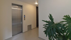 A hallway with a metallic elevator, a vent, and a large green plant. - Coahuila, in the heart of Roma Norte (Ciudad de México)