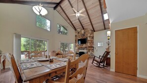A spacious dining area with a large wooden table, multiple chairs, and a stone fireplace.