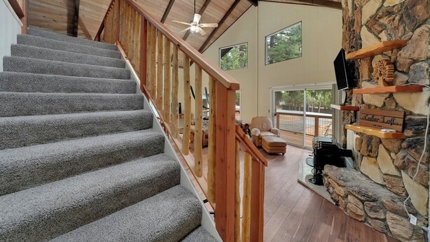 A staircase with wooden railings, a stone wall, and a ceiling fan.