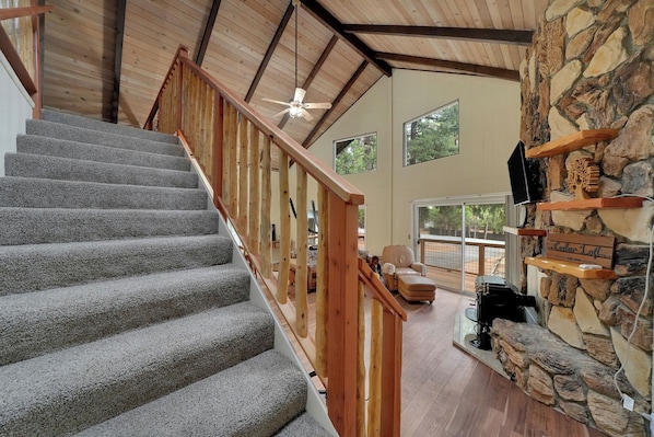A staircase with wooden railings, a stone wall, and a ceiling fan.
