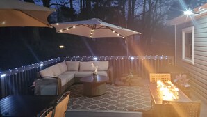 Une terrasse extérieure avec un canapé incurvé, une table basse ronde et un petit foyer.