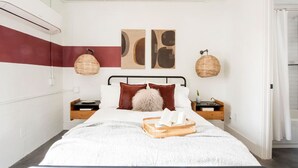 A neatly arranged bedroom with a bed, bedside tables, and wall art. - The Scarlet – Midtown Apt w/ Balcony & Skyline (Atlanta)