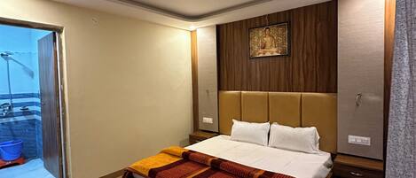 A modern hotel room with a large bed, wooden headboard, and a picture of a Buddha on the wall.