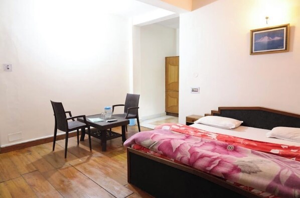 A small, well-lit room with a bed, a desk with two chairs, and a wooden wardrobe. - Hotel paradise hills (Dalhousie)