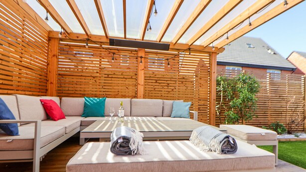 A covered outdoor seating area with a sofa, a table, and a bench. - 37 Devana Gardens (Chester)