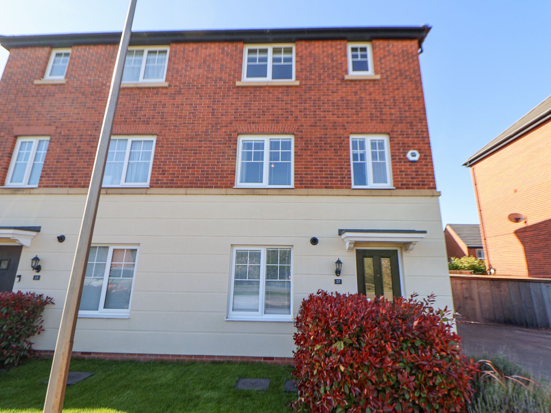 A two-story residential building with a flat roof, brick facade, and white-framed windows.