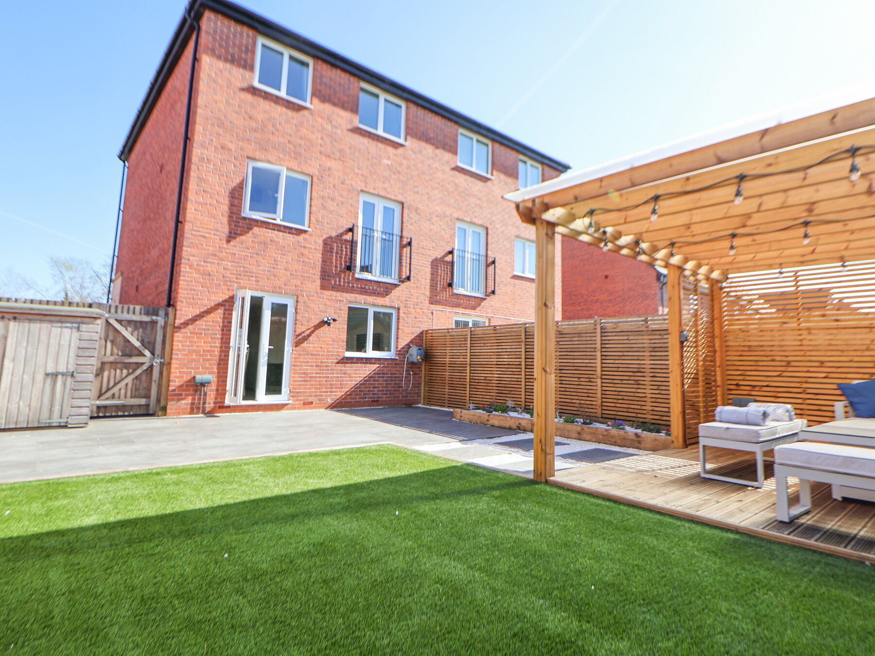 A two-story brick building with a wooden deck and a covered patio area.