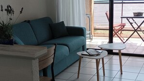 Relax in this inviting living area with a sofa, side table, and small table, offering a view of the outdoor space.