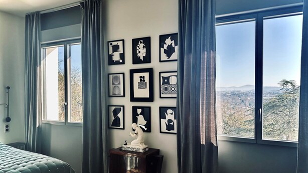 A bedroom with a bed, a dresser, and a wall of framed artwork. - JADE (double room with sitting area) (CARCASSONNE)