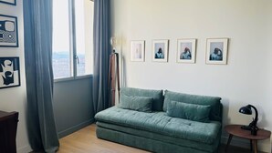 A room with a green sofa, a floor lamp, and four framed pictures on the wall. - JADE (double room with sitting area) (CARCASSONNE)
