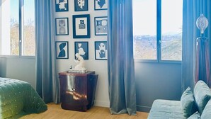 A modern room with a large window, a wooden floor, a green sofa, a small cabinet, and a ceiling light. - JADE (double room with sitting area) (CARCASSONNE)