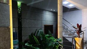 Ein Empfangsbereich mit einem hölzernen Pflanzgefäß mit der Aufschrift "La Rambla", einem Wasserspender und einer Treppe im Hintergrund.