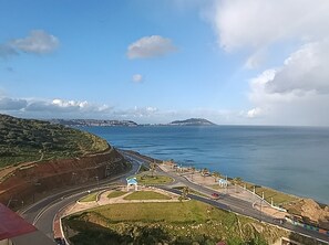 A coastal road with a roundabout, a bridge in the distance, and a view of the sea. - La Résidence La Rambla (Fnideq)