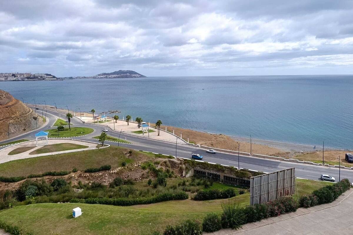 A coastal road with a roundabout, a beach, and a distant island.