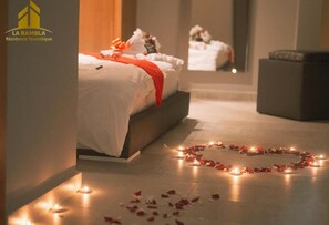 A hotel room with a bed, a heart-shaped arrangement of candles and rose petals on the floor, and a mirror reflecting the room. - La Résidence La Rambla (Fnideq)