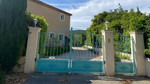 A gated entrance to a building with a tiled roof and a light-colored facade.