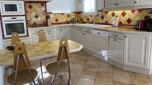 A kitchen with white cabinets, a tiled backsplash, and a dining area with a table and chairs.