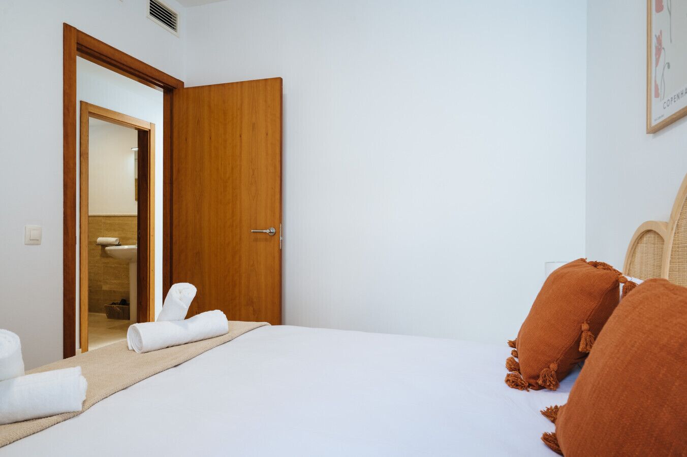 Une chambre d’hôtel avec un lit, une porte en bois et une salle de bain visible à travers une porte ouverte.