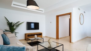 Een moderne woonkamer met een bank, een salontafel, een televisie en een houten kast.