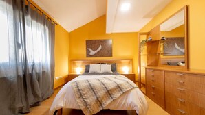 Un dormitorio con cama, mesitas de noche, cómoda, espejo y una obra de arte en la pared.