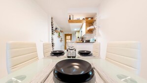 Comedor con una mesa de vidrio, dos platos negros y una copa de vino.