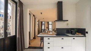 A modern kitchen with a black stove, white cabinets, and a window overlooking a cityscape.
