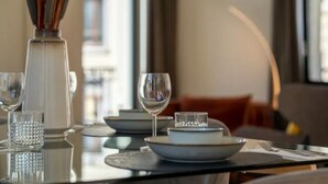A dining table set with plates, glasses, and cutlery, with a vase and candle in the background.