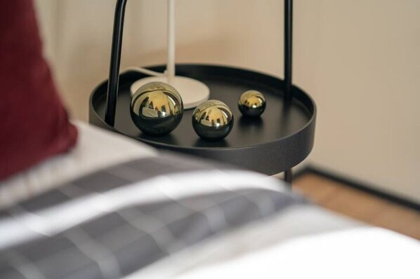 A bed with a black and white striped blanket and a black bedside table with three spherical objects on it.