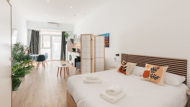 A modern hotel room with a large bed, a small desk, and a kitchenette. - Stylish Studio with Easy Access to Valencia's Best (València)