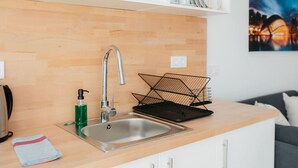 A modern kitchen with a stainless steel sink, wooden countertop, and a black wire basket. - Stylish Studio with Easy Access to Valencia's Best (València)