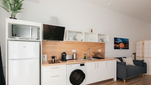 A compact kitchen with a microwave, toaster, sink, and washing machine. - Stylish Studio with Easy Access to Valencia's Best (València)