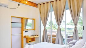Ein Hotelzimmer mit einem Bett, einer Holzablage mit Toilettenartikeln, einem Spiegel und einem fenster mit Vorhängen.