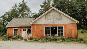 A wooden cabin with a gabled roof, large windows, and a door with a circular window.