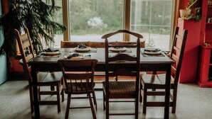 A dining table with four chairs, a Christmas tree, and a stained glass window in the background.