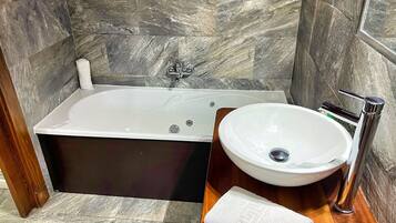 A modern bathroom with a freestanding bathtub, a round sink, and a wooden vanity.