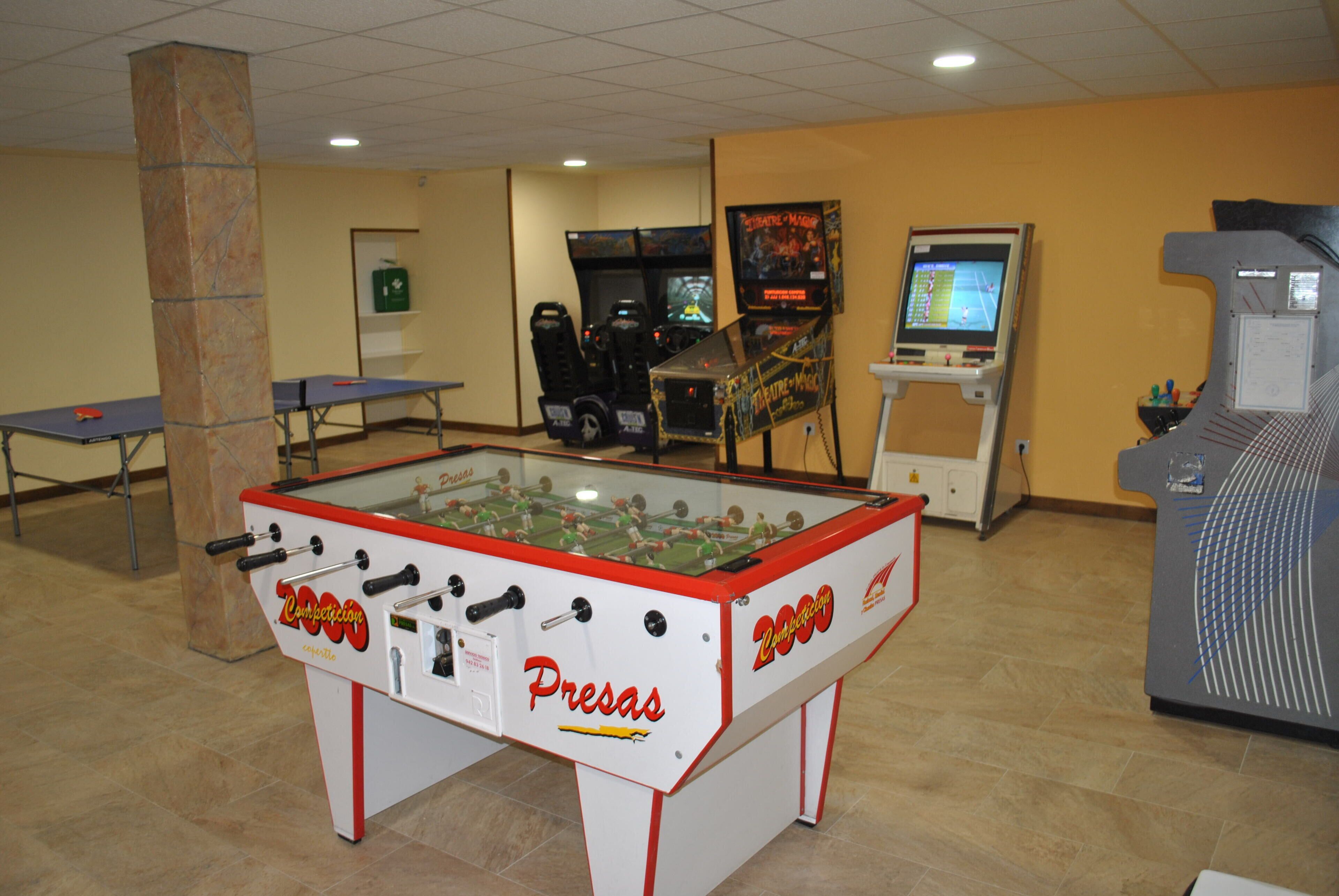 Una habitación con mesa de fútbol de mesa, mesa de ping pong y una mesa de fútbol de mesa con la marca 'Pressas'.
