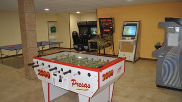 Una habitación con mesa de fútbol de mesa, mesa de ping pong y una mesa de fútbol de mesa con la marca 'Pressas'.